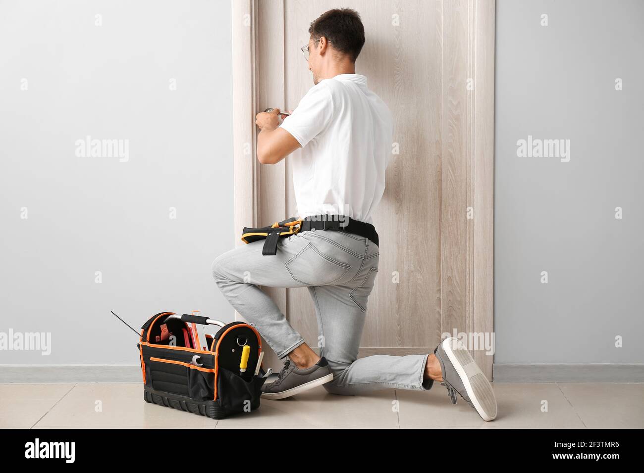 Construction worker repairing door indoors Stock Photo