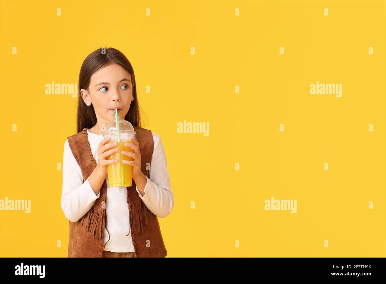 Cute little girl drinking orange juice on color background Stock Photo ...