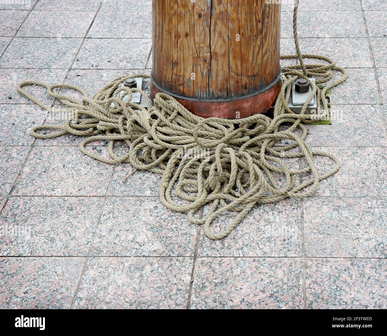 A large amount of rope around the bottom of a wooden mast. Stock Photo