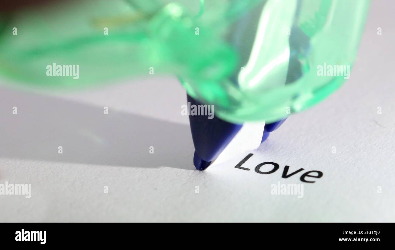 The word or text 'love' about to be removed, hidden, erased or covered up by correction tape. Close up detail Stock Photo