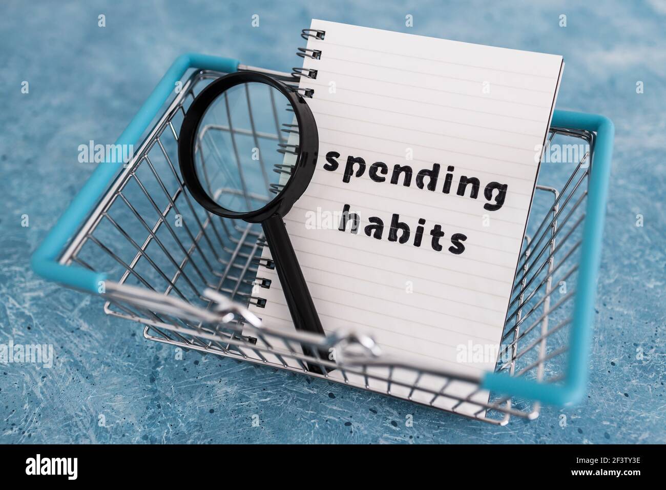spending habits text on notepad with shopping basket and magnifying ...