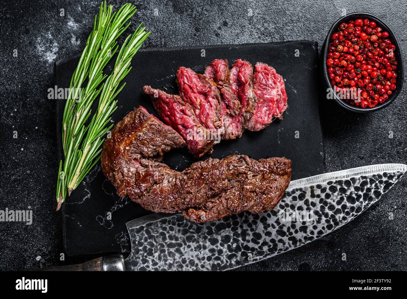 Sliced grilled Onglet Hanging Tender steak on a marble board. Black background. Top view Stock Photo