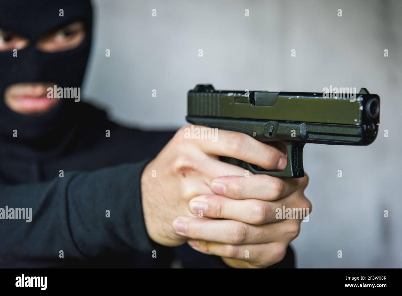 Robbery in store. Robber is aiming and threatening with gun in shop. Stock  Photo