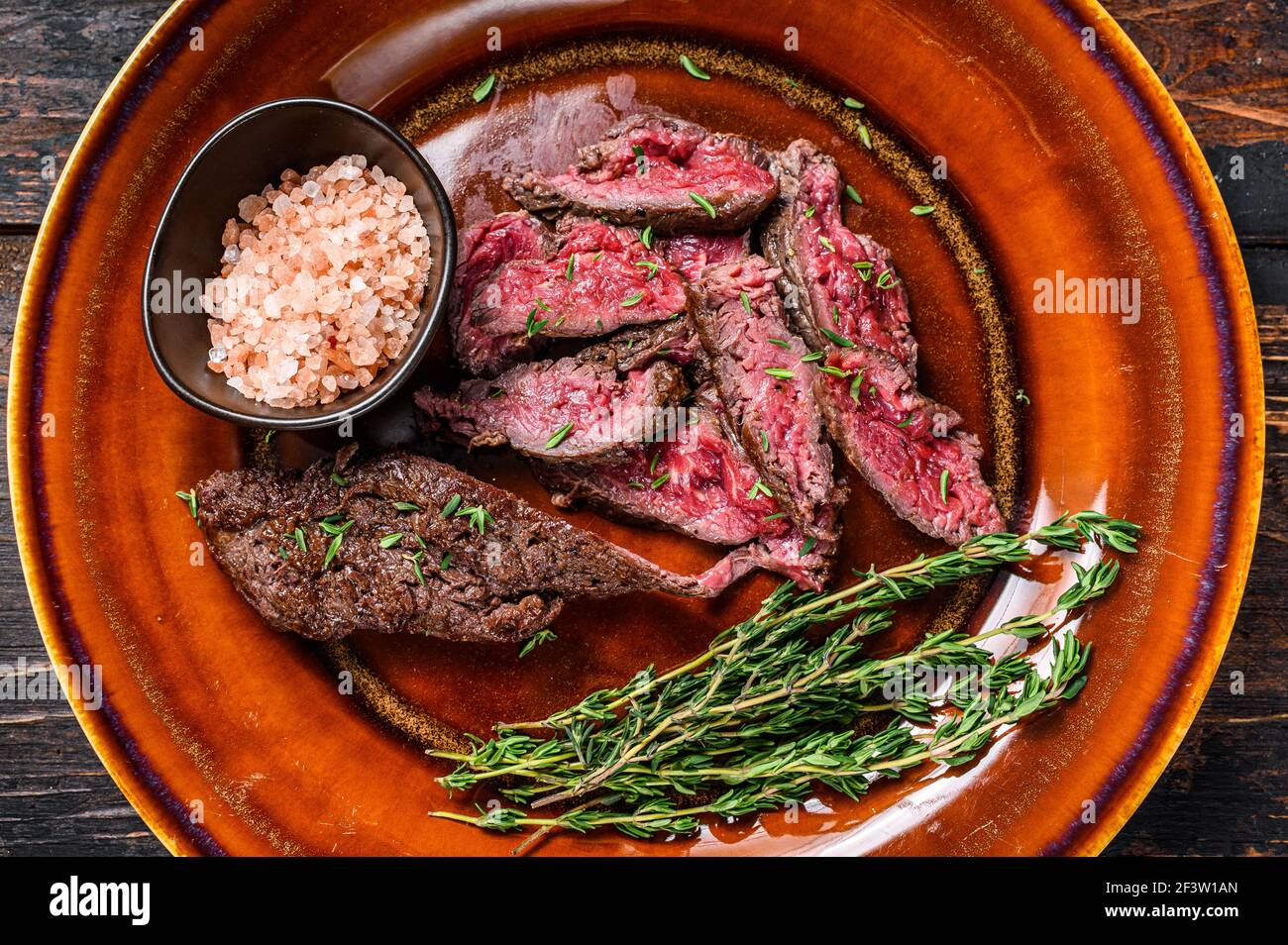 Medium rare Sliced grilled Onglet Hanging Tender meat beef steak on a plate. Dark wooden background. Top view Stock Photo