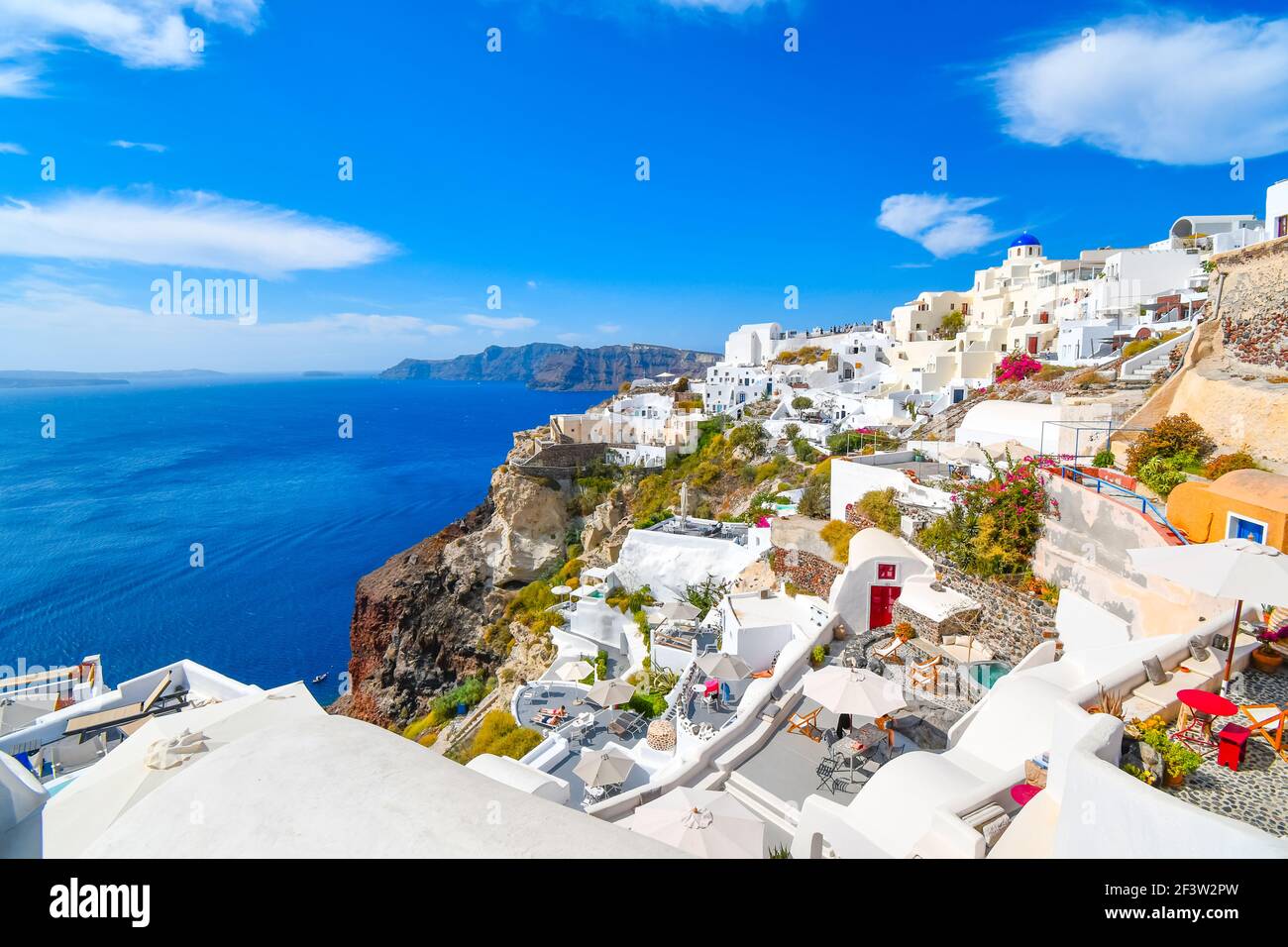 The steep cliffs of the caldera, the Aegean Sea and the whitewashed village of Oia with the Blue Dome Church in view on the island of Santorini Greece Stock Photo