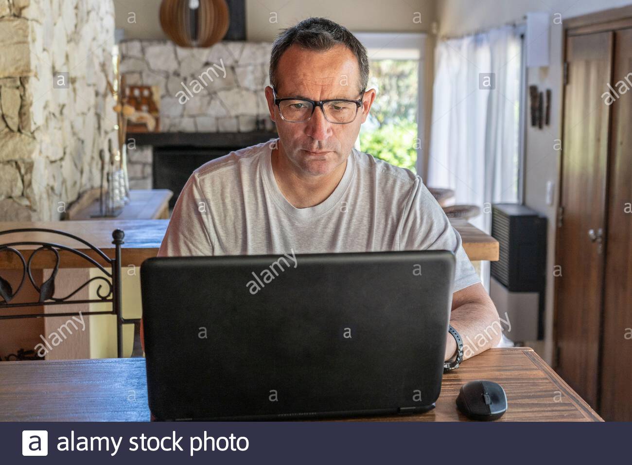 A man working at home, using a laptop computer, using internet, reading news, doing online shopping order for delivery, or studying with device online Stock Photo