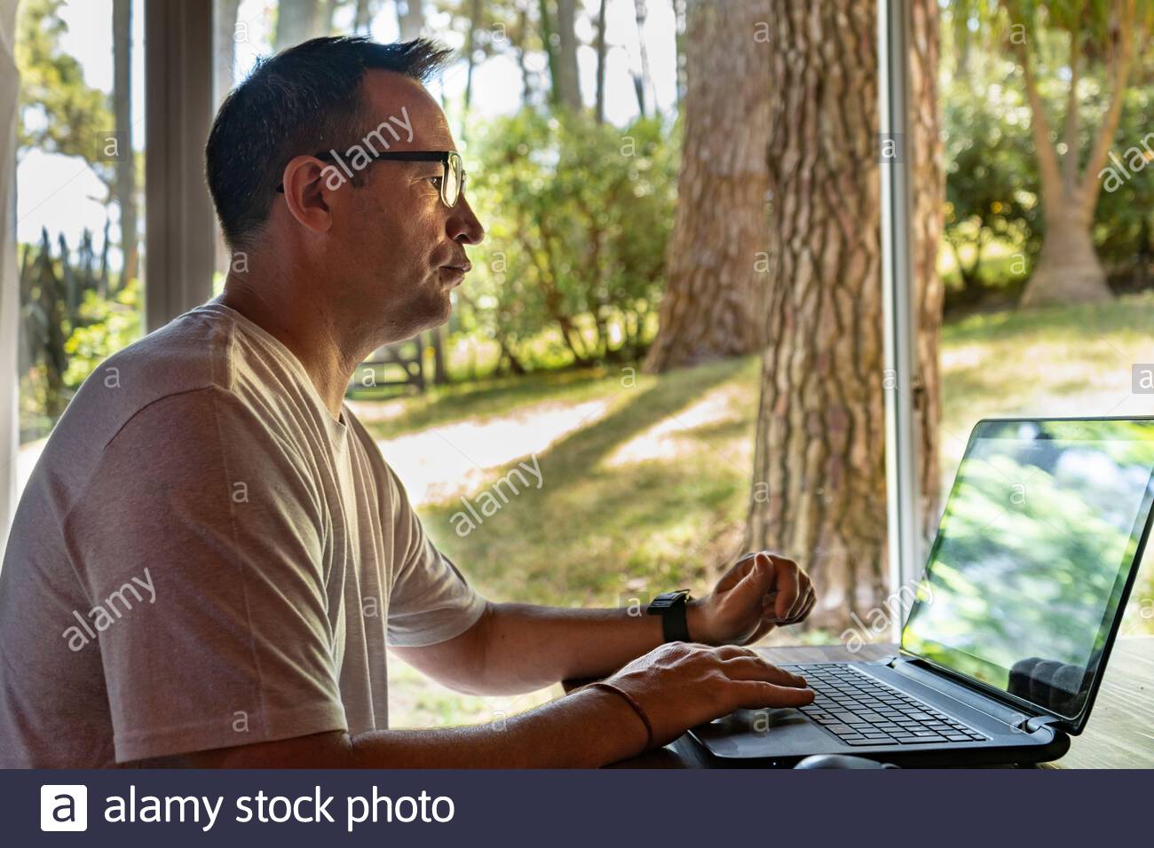 A man working at home, using a laptop computer, using internet, reading news, doing online shopping order for delivery, or studying with device online Stock Photo