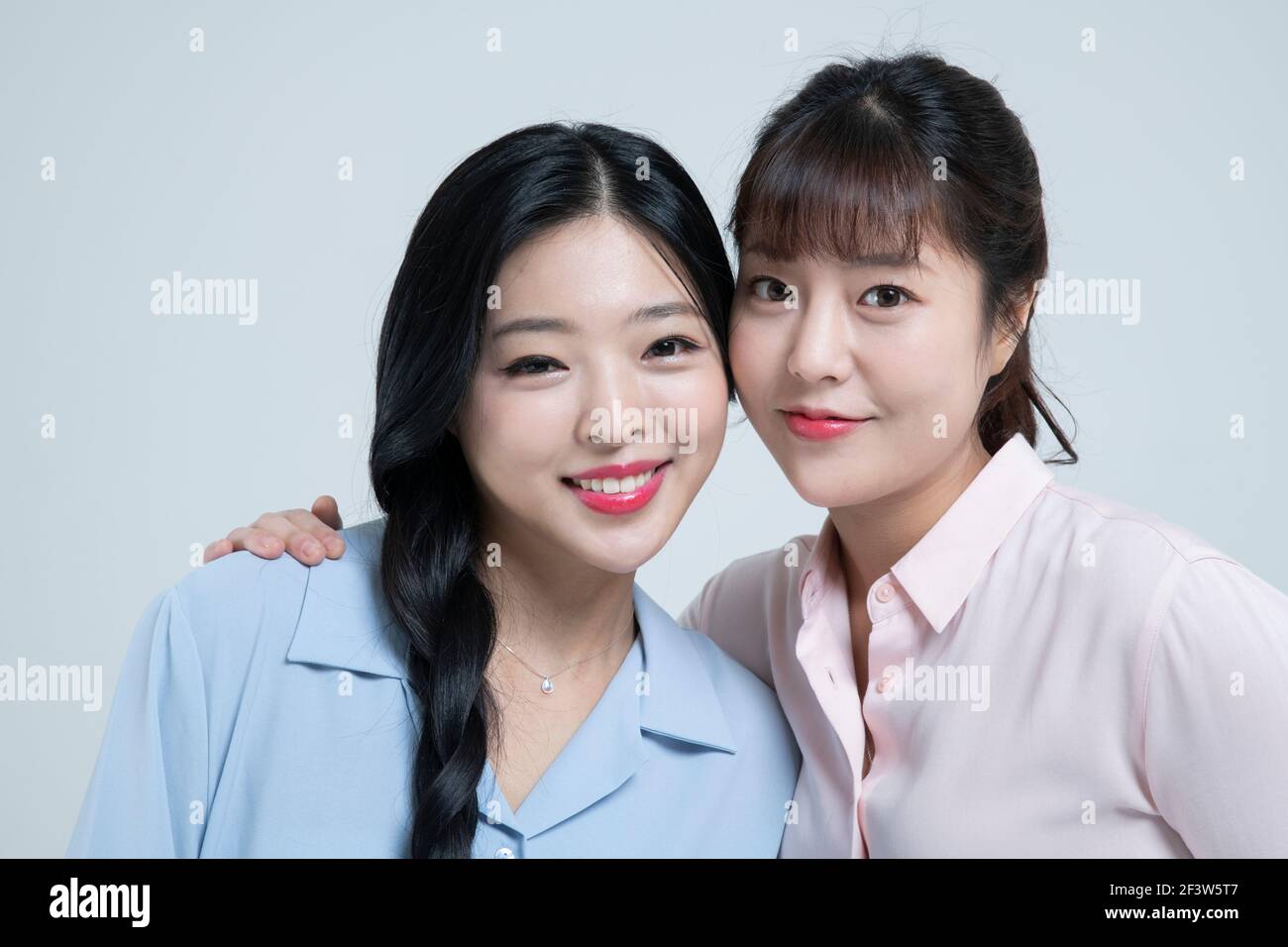 two beautiful Asian women, sisters with hands under chin Stock Photo