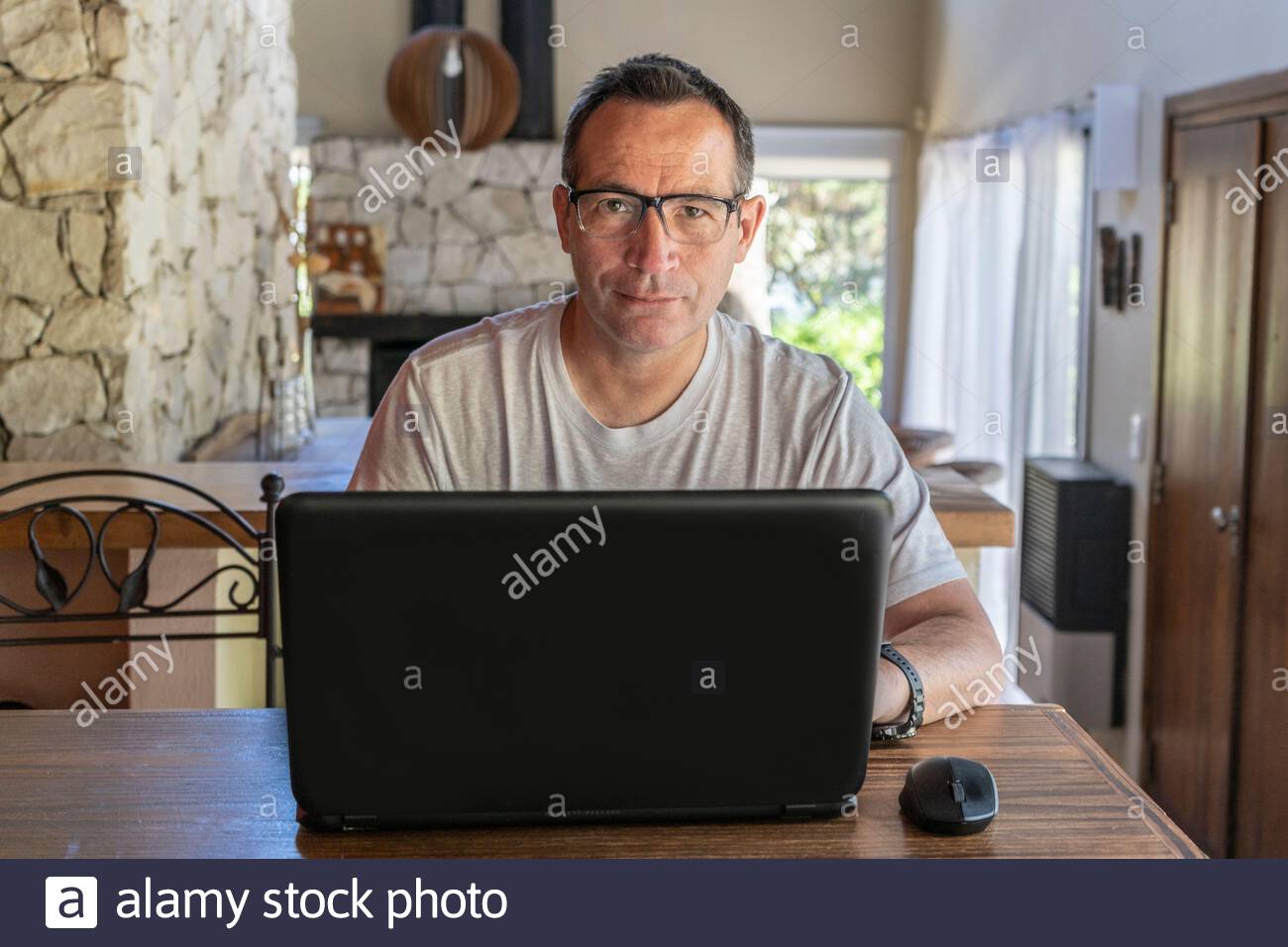 Portrait of a good looking man working at home on some project at a table looking at camera. Stock Photo