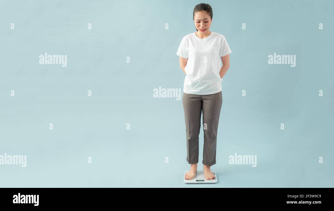 Asian beautiful woman standing on the Weight Scale at home gym ...