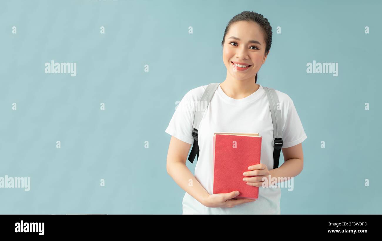 Portrait of a happy friendly girl student with backpack holding books ...
