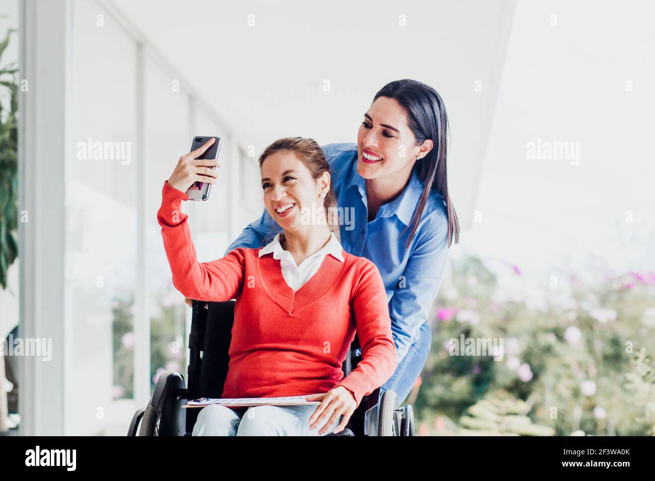 Young latin woman in wheelchair taking a selfie photo at workplace with ...