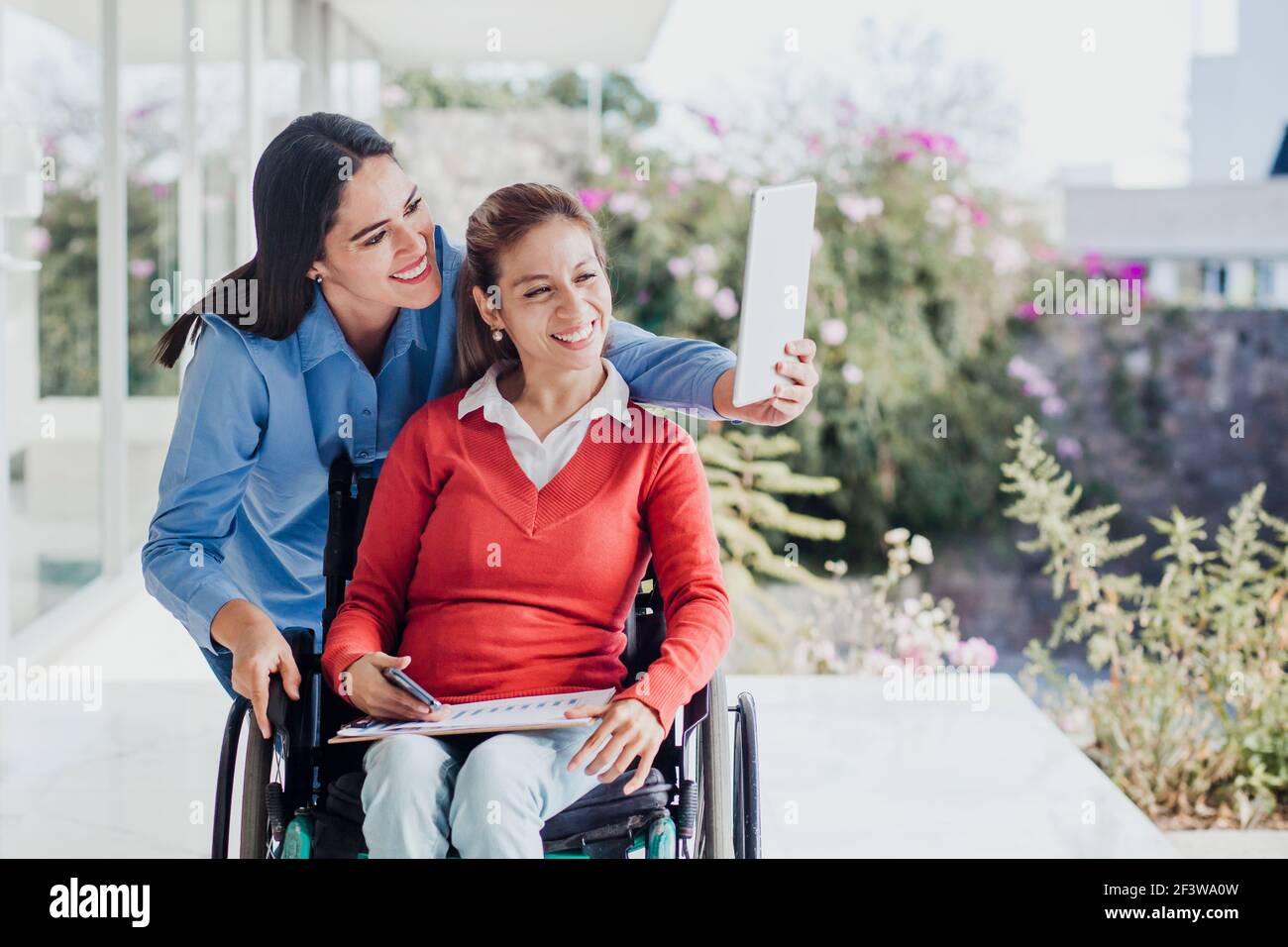 Young latin woman in wheelchair taking a selfie photo at workplace with ...