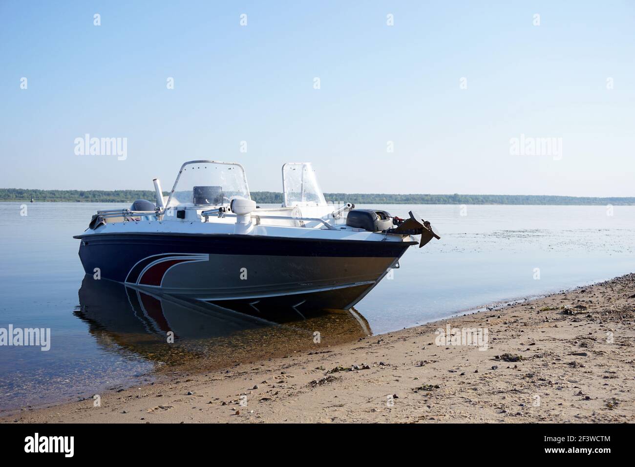 A motorboat stands on the sandy bank of the river without people. Stock Photo