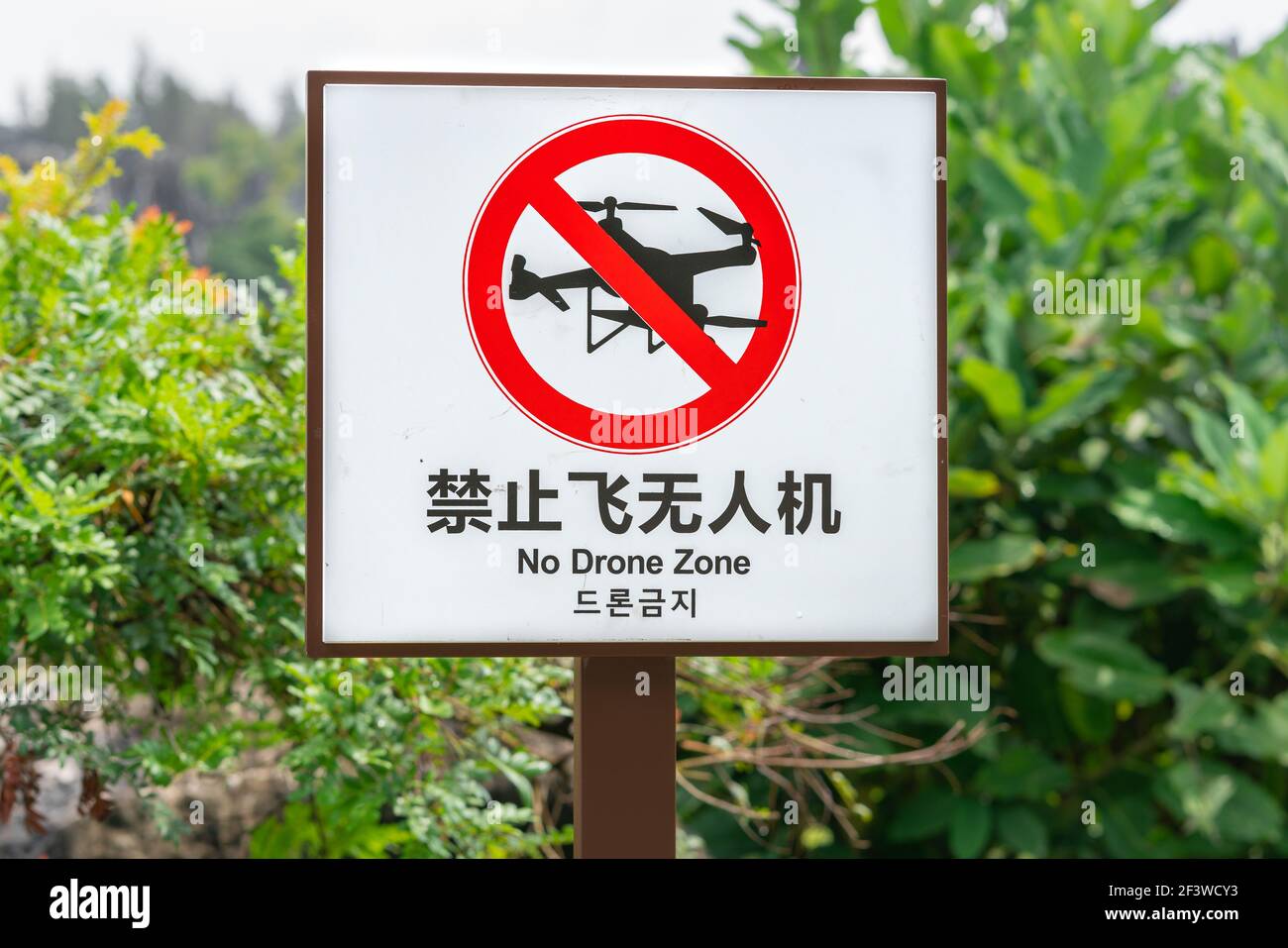 No drone zone board written in Chinese English and Korean language with logo to ban drone flying in the area ( translation : no drone zone ) Stock Photo