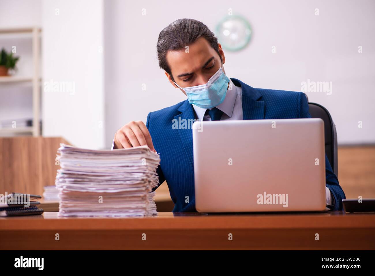 Young employee working in the office wearing mask Stock Photo - Alamy
