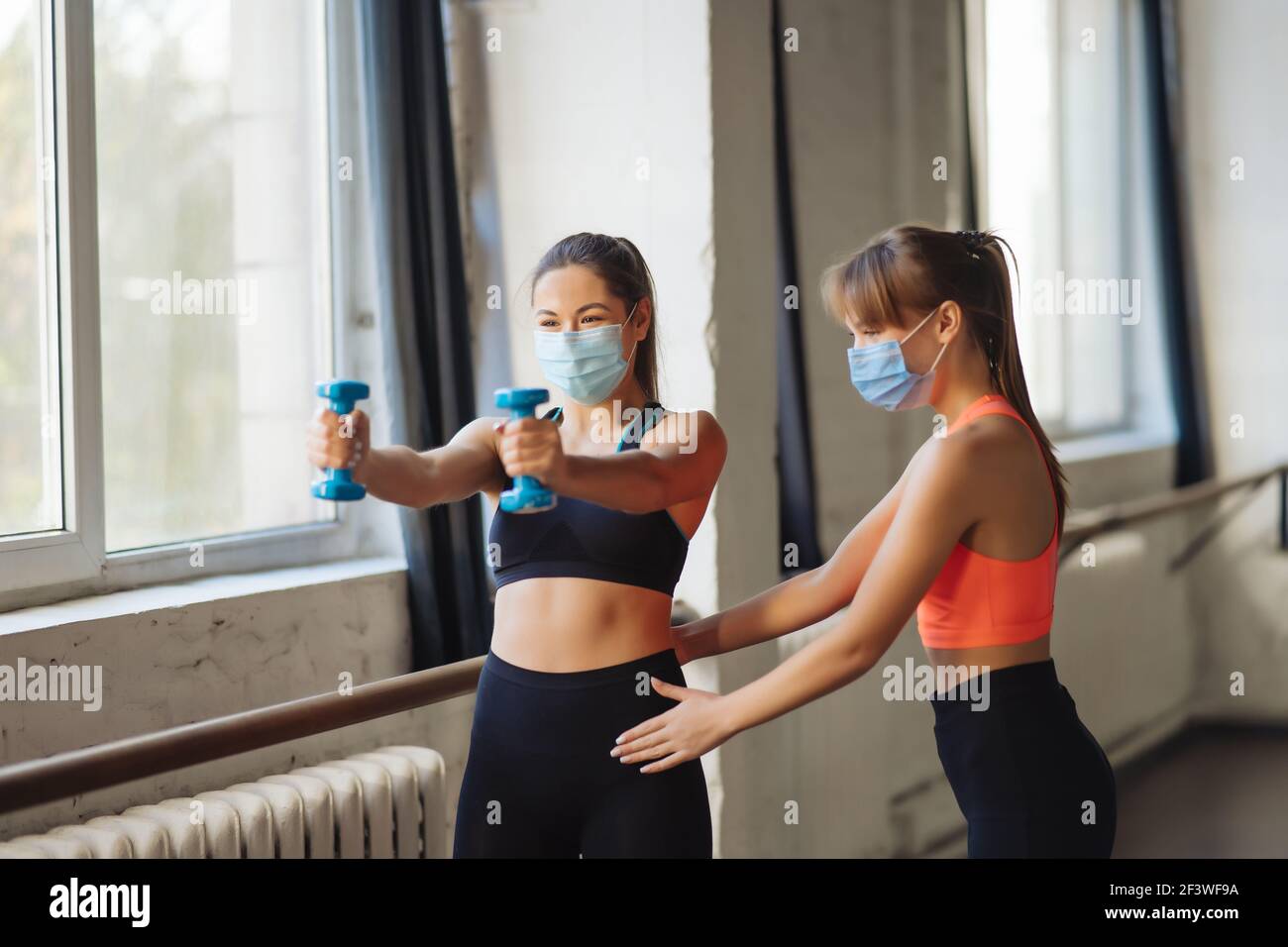 Young woman personal trainer helping with workout at gym Stock Photo ...