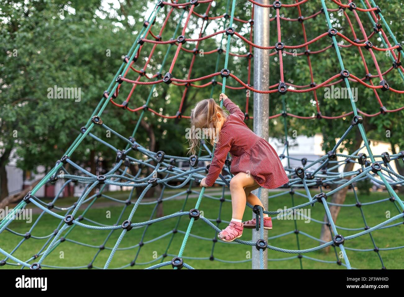 playground under looking up ladies dresses little girl in red dress playing on the on a summer day. Healthy summer activity for children Stock Photo Edit:Spring