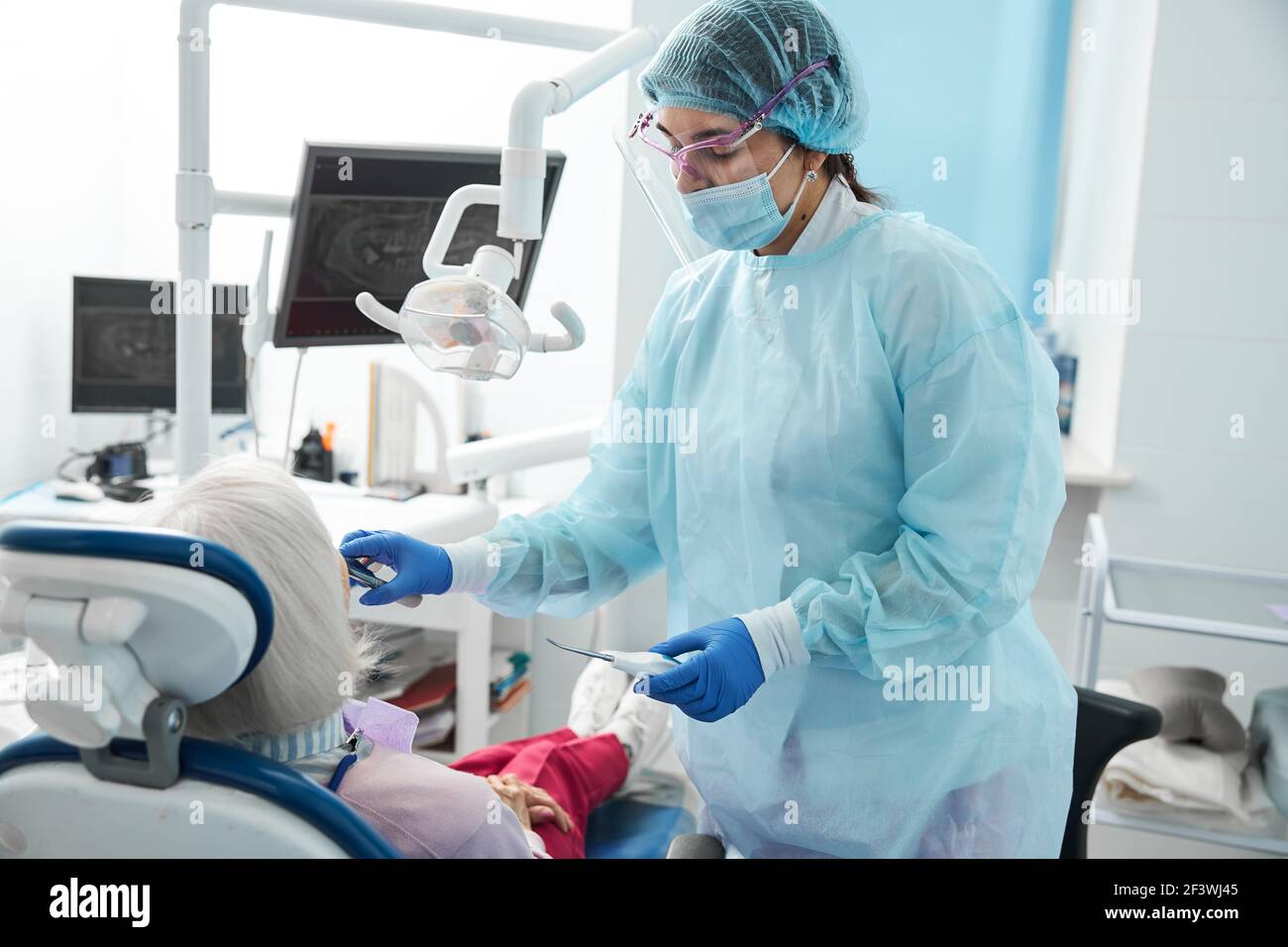 Female dental surgeon doing a dental extraction on patient Stock Photo