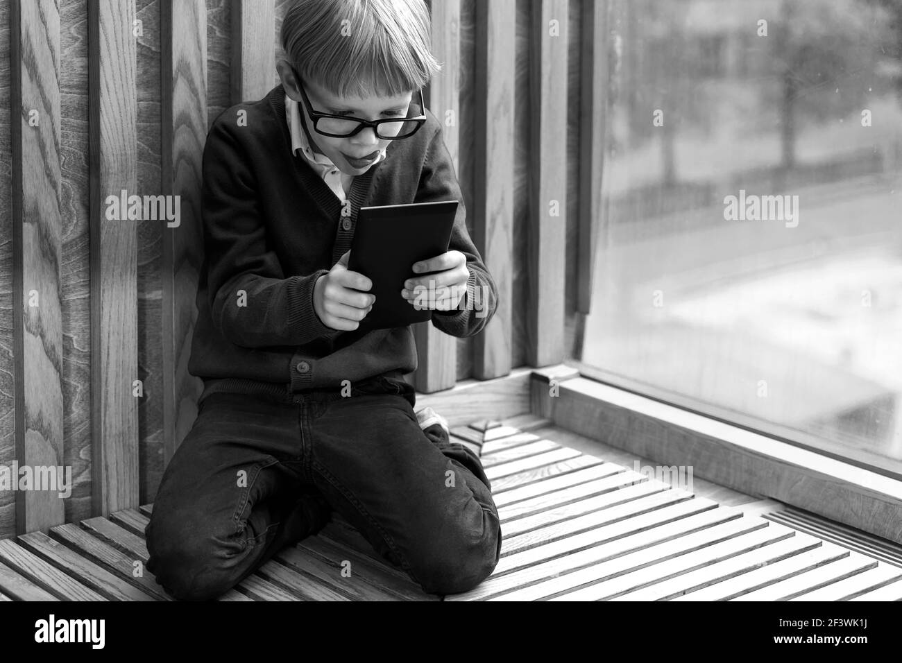 boy 6 years old plays with enthusiasm look into the tablet. monochrome image Stock Photo