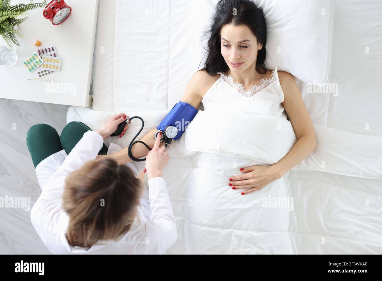 Nurse measures blood pressure of woman in bed Stock Photo Alamy