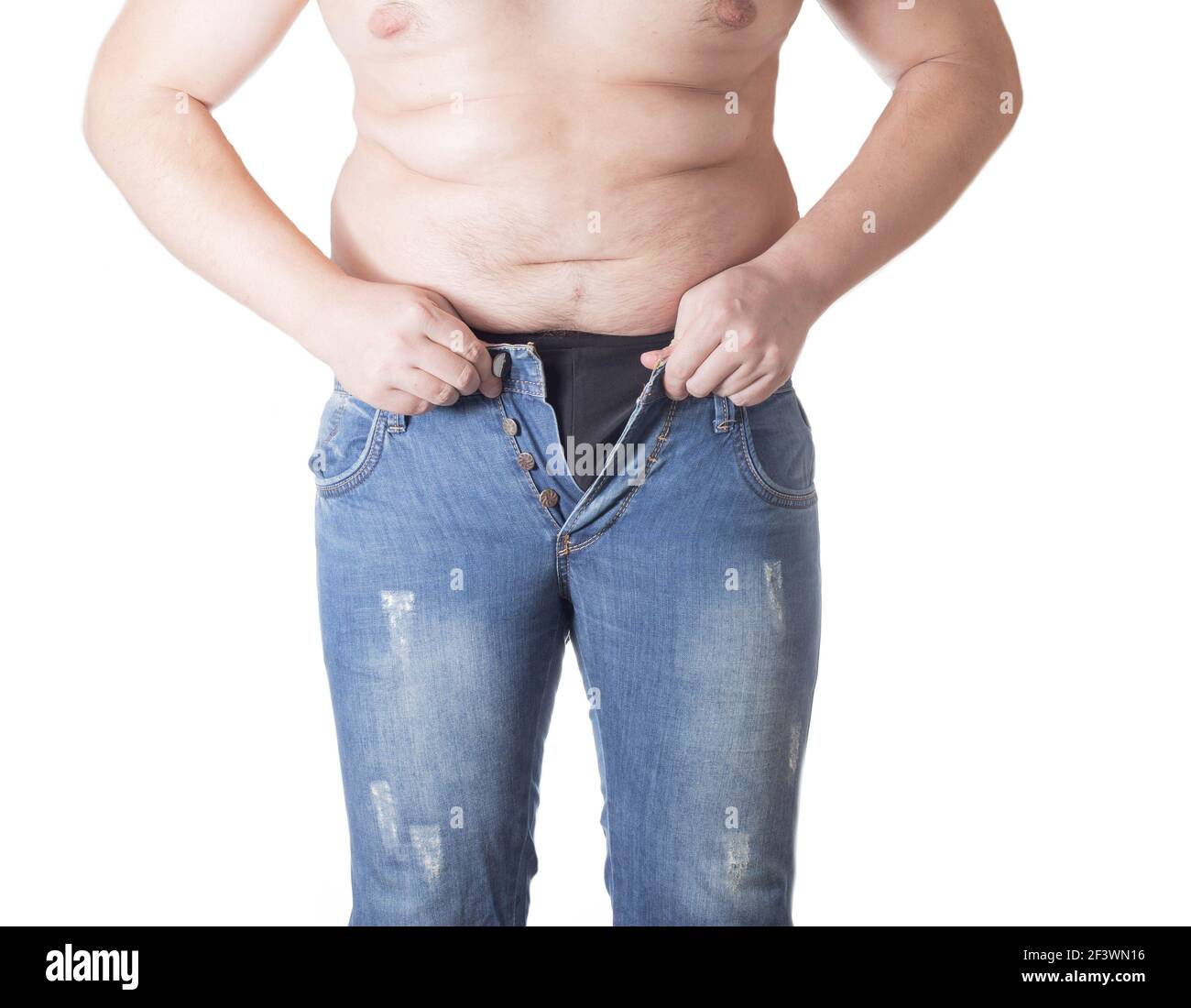 An obese man tries to put on tight little shorts on a white background