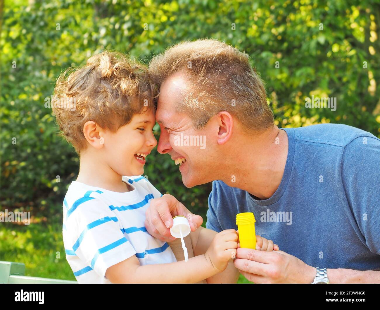 Father and son blow bubbles. They enjoy communicating with each other, have fun and laugh. Stock Photo