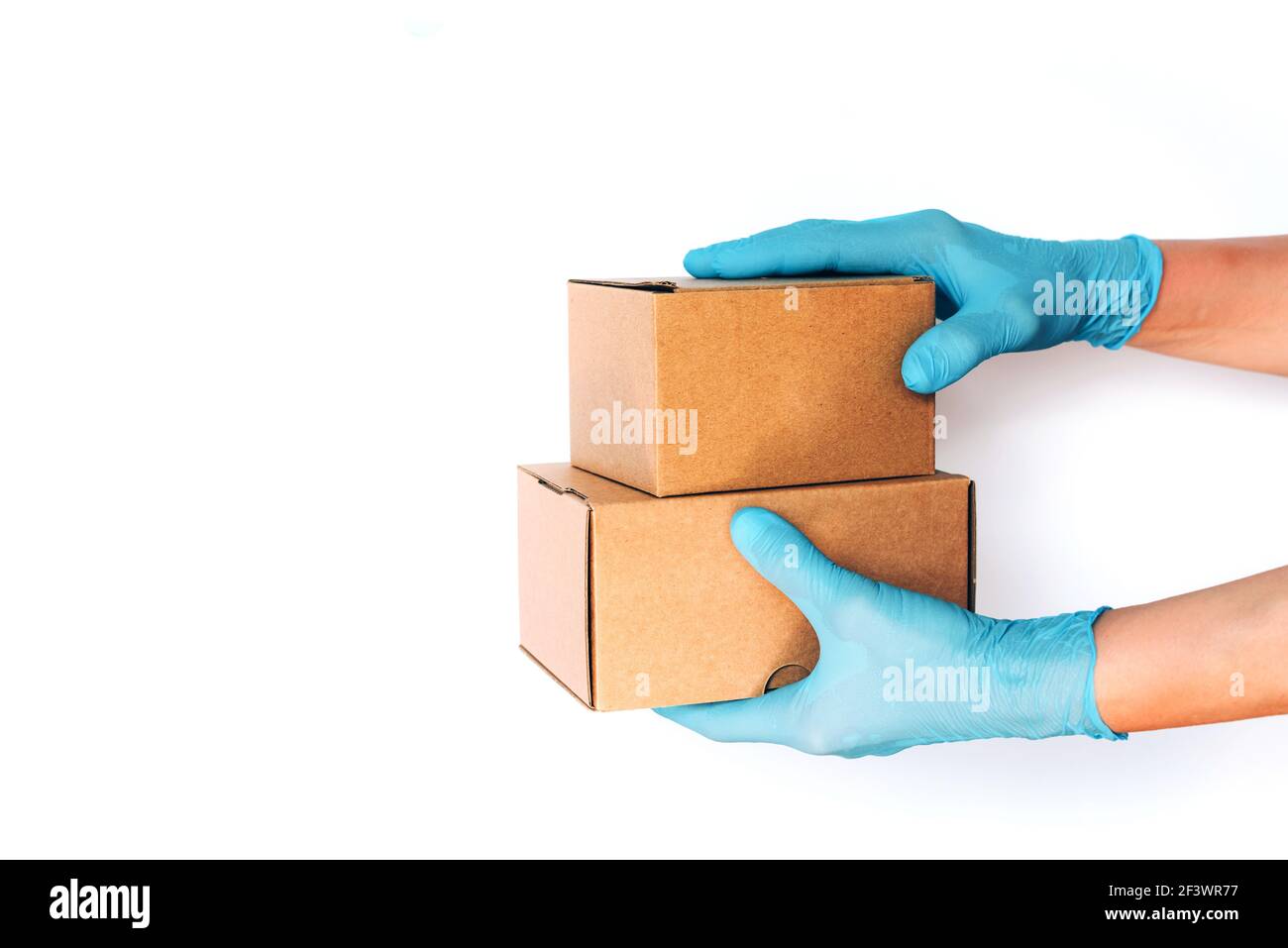 Hand in medical glove gives craft box over blue background. Contactless online shopping concept. Banner, copy space. Fast and free delivery transport Stock Photo