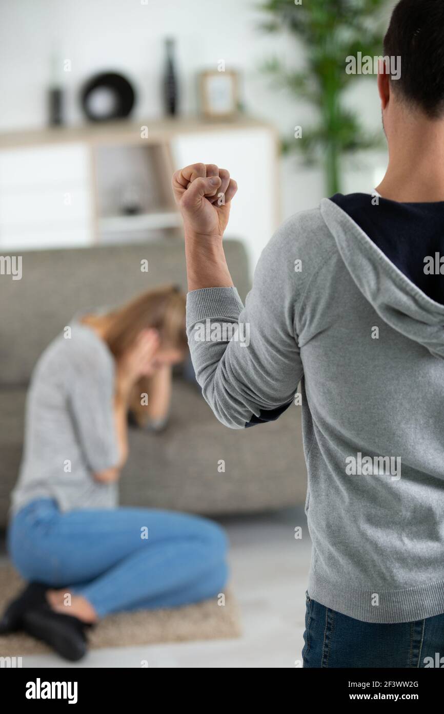 man raising his fist to cowering woman Stock Photo