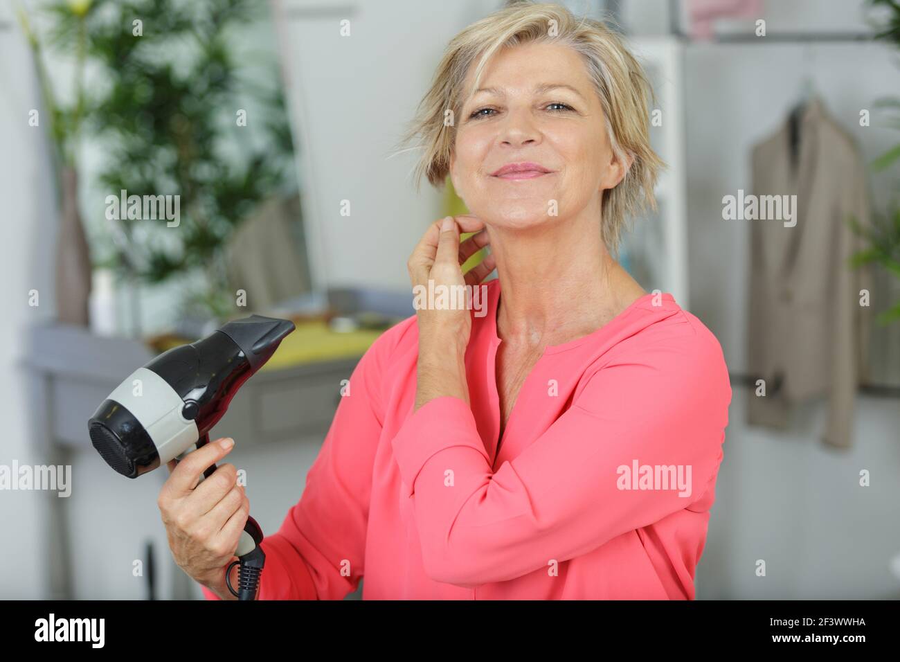 Mature woman blow drying hair hi-res stock photography and images - Alamy