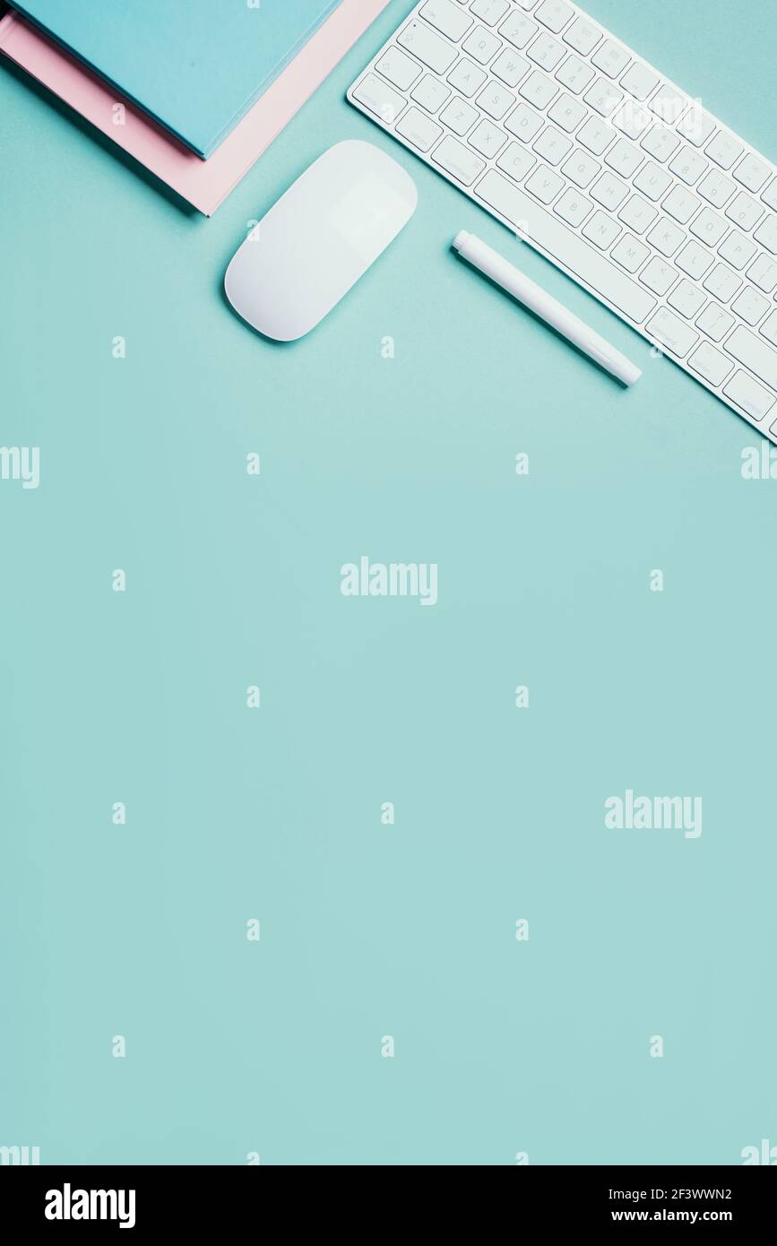 Home designer office workspace. White mouse, keyboard, notebook, pen on blue background. Top view. Copy space. Flat lay. Remote job, work. Feminine Stock Photo