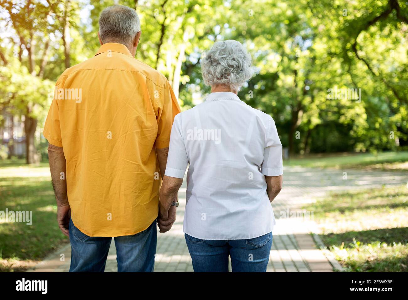 Old senior couple together walk through the park Stock Photo