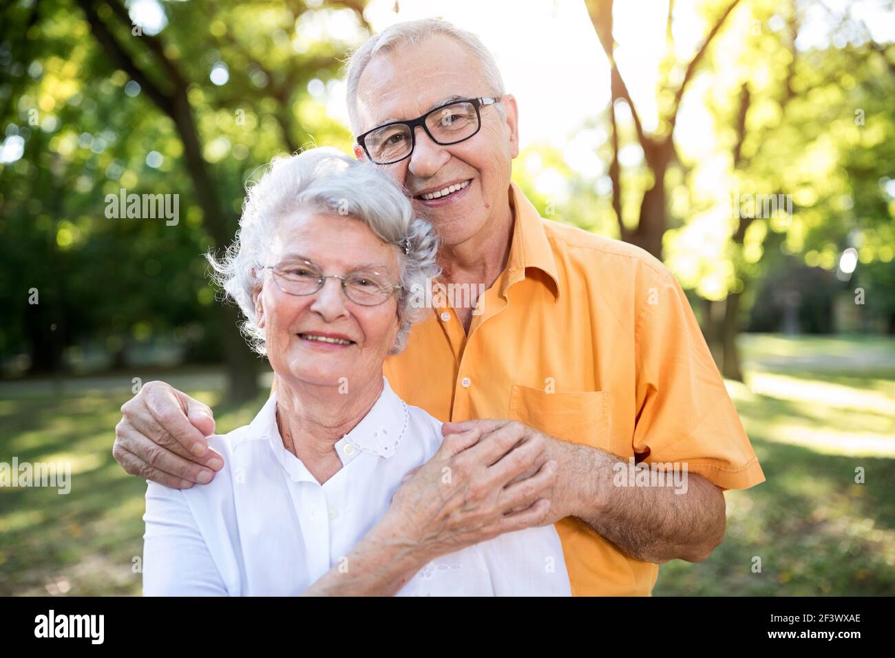 Happy and handsome senior couple hugging in park Stock Photo - Alamy