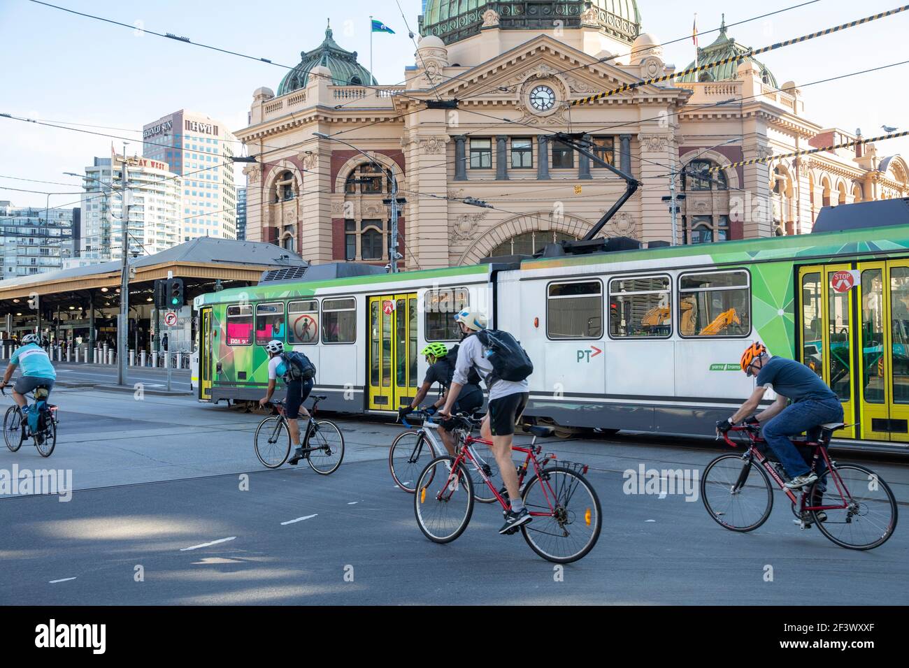 Melbourne cyclists and melbourne tram commuting travel past Flinders street railway station,Melbourne city centre,Victoria,Australia Stock Photo