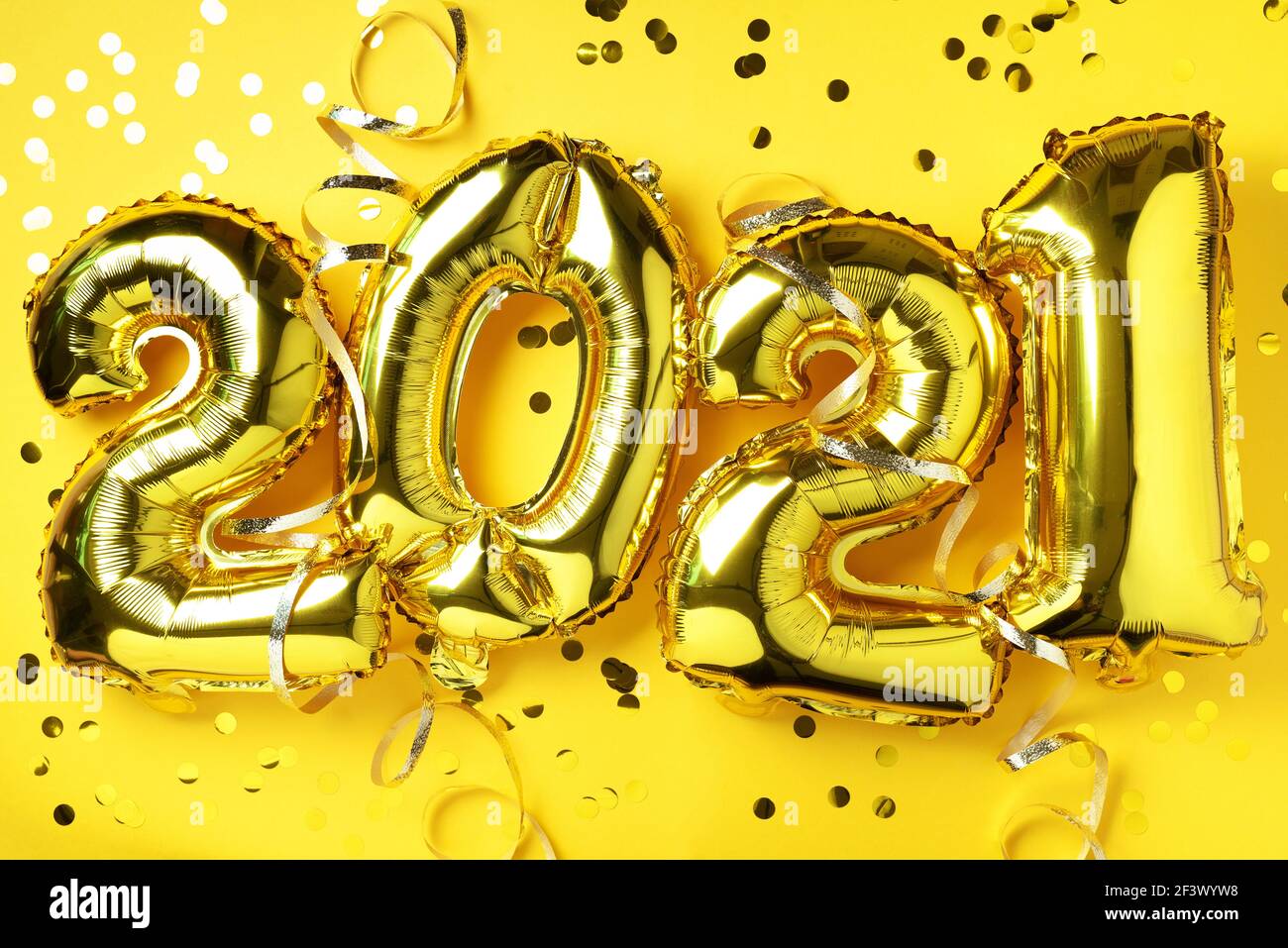 Golden foil balloons made numbers 2021 on yellow background with light ...