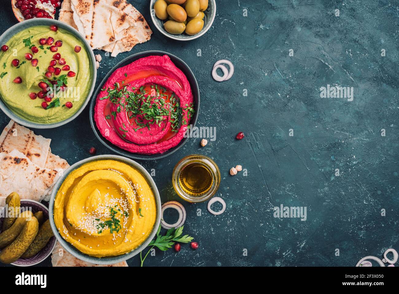Colorful hummus bowls - green, yellow and beetroot hummus on dark ...