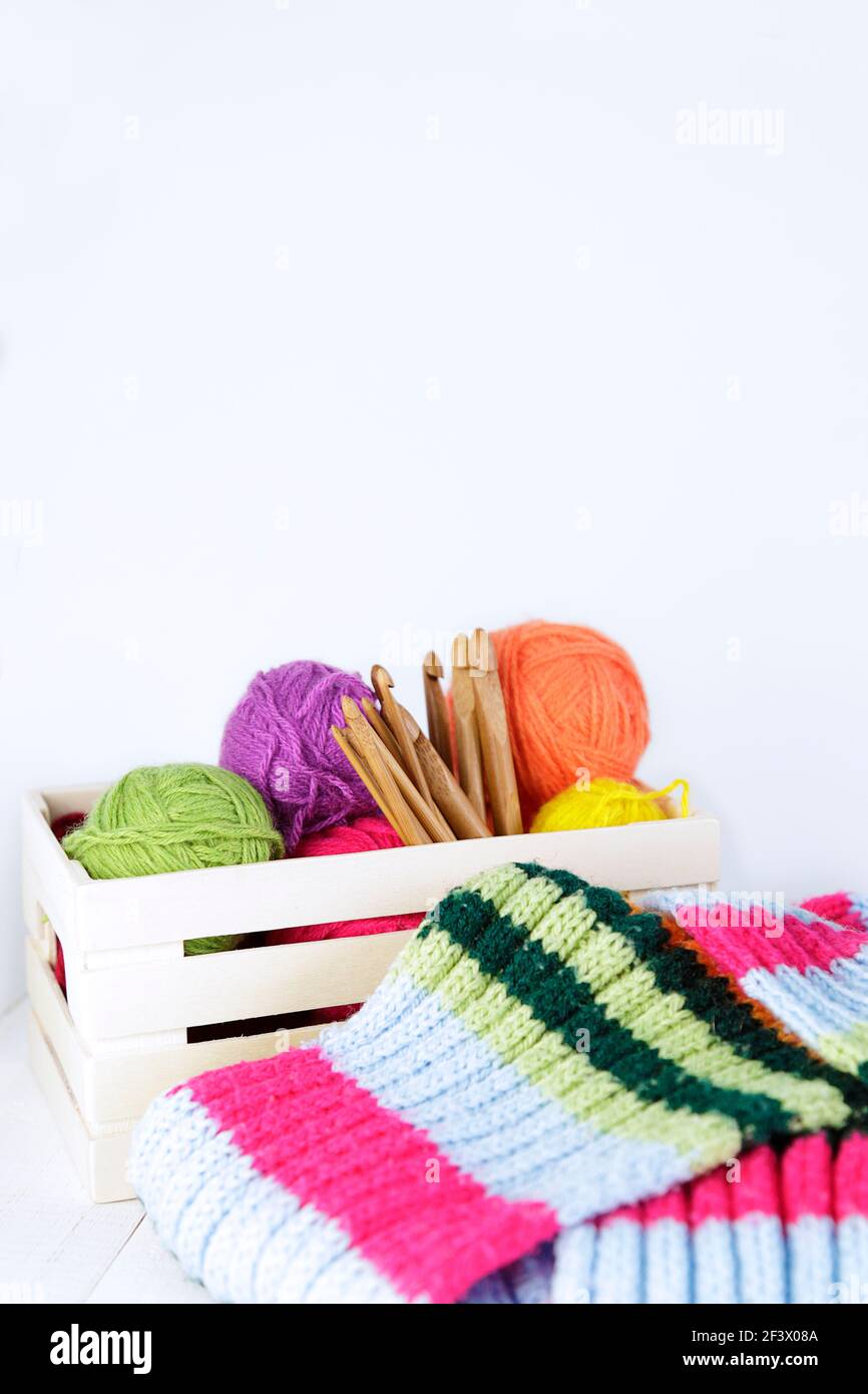 Wooden box with natural bamboo crochet hooks and different color yarn balls of wool. Copy space. Stock Photo