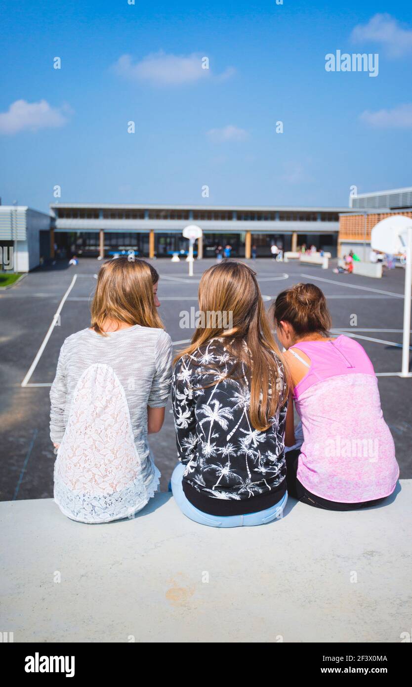 Atmosphere with pupils in the schoolyard of the “College Simone Veil” junior high school in Crevin (Brittany, north-western France). Three girls viewe Stock Photo