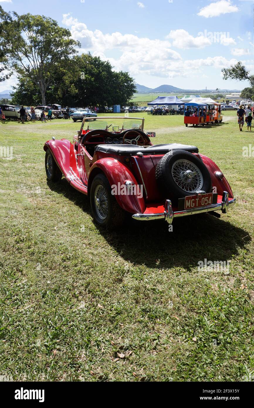 A classic red MG sports car from 1954, restored on display at a country