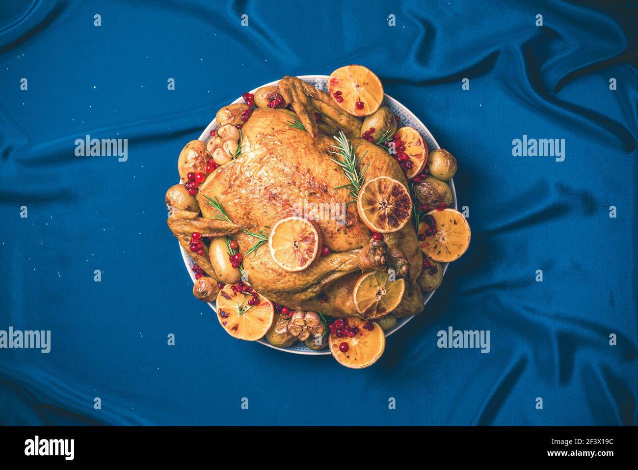 Roasted chicken with oranges, rosemary and cranberries on plate over concrete background. Traditional Thanksgiving or Friendsgiving holiday Stock Photo