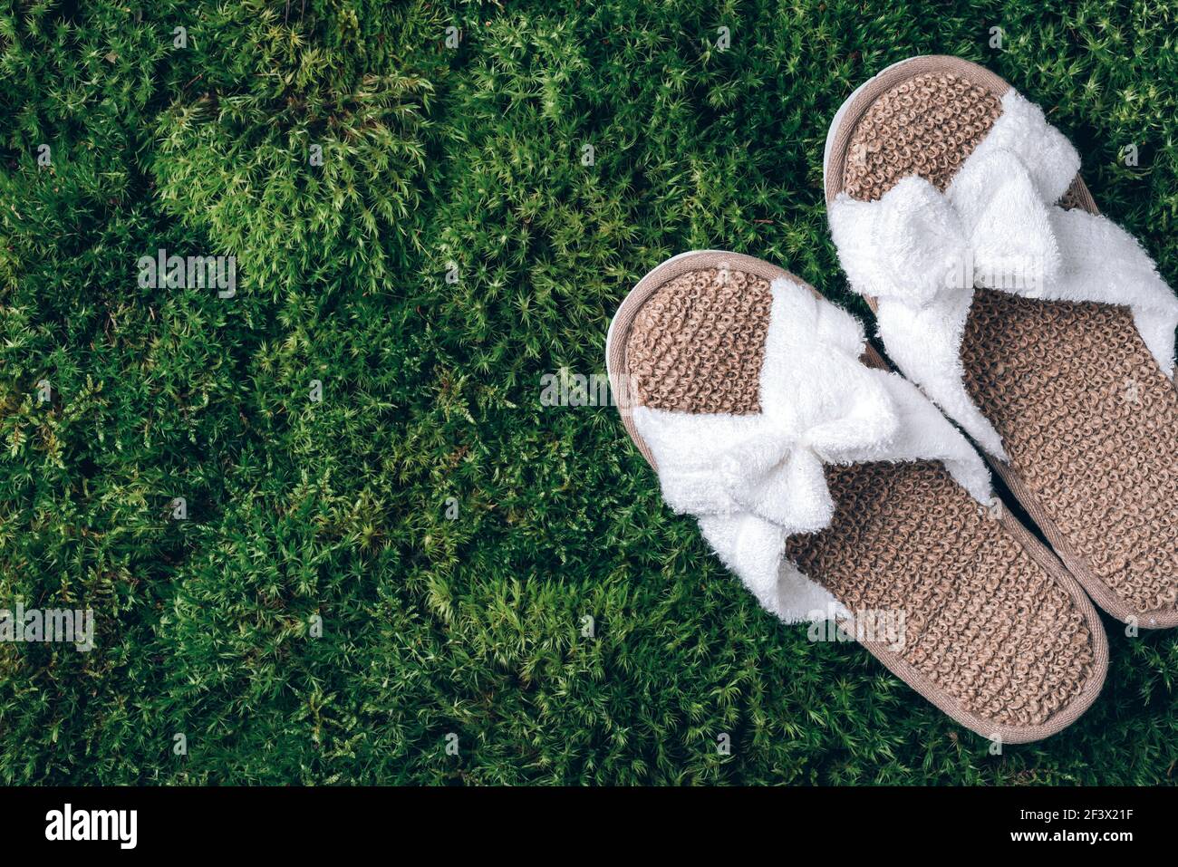 Spa slippers on green moss texture. Top view. Copy space. Zero