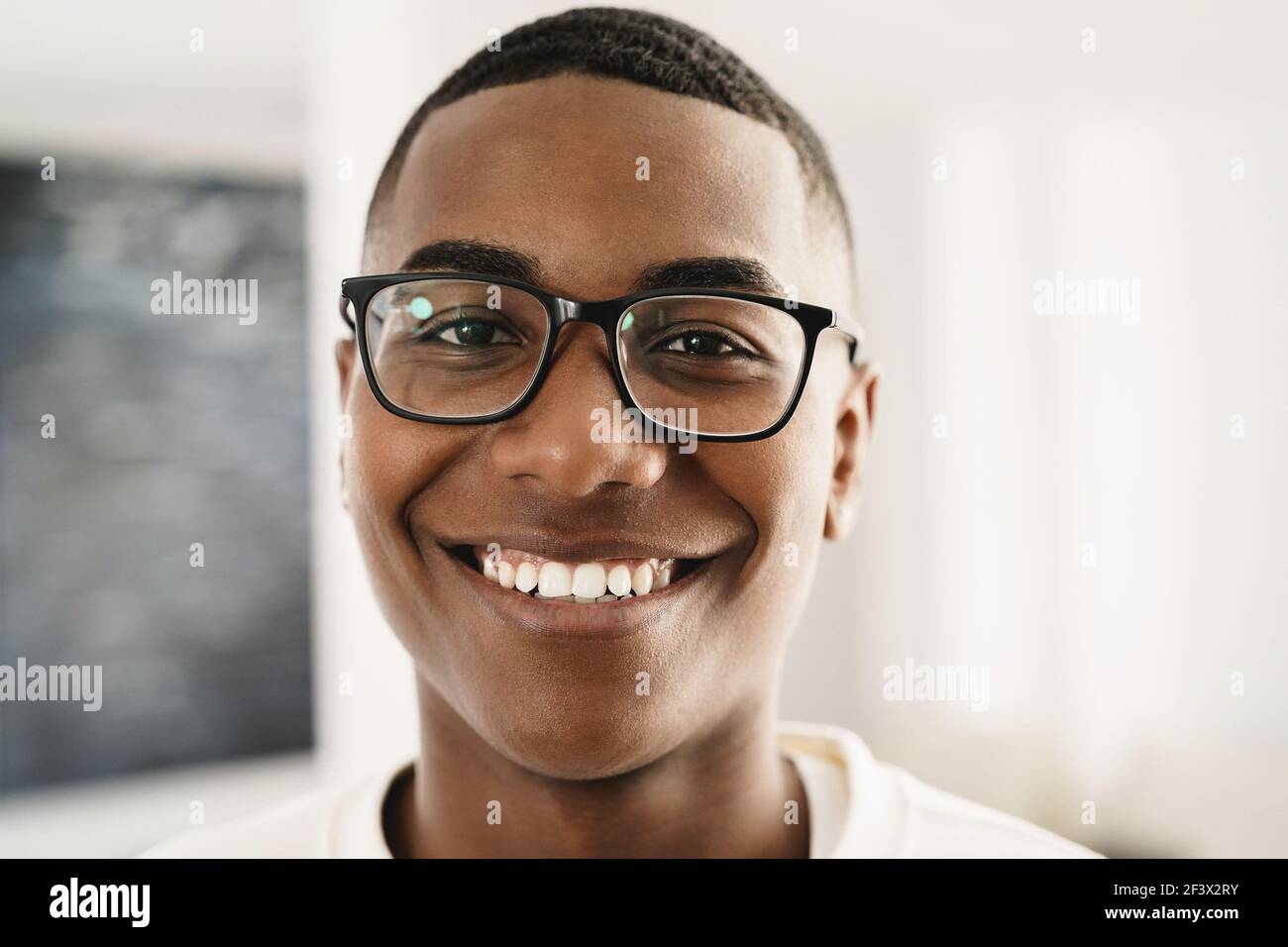 Happy young african man looking at camera indoors at home - Focus on ...
