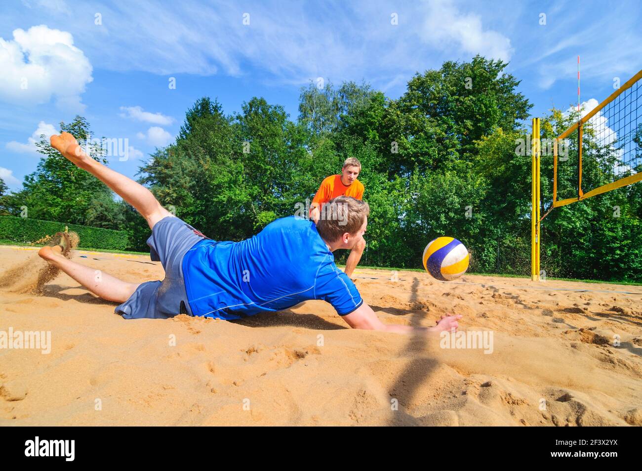 Intensive game on beachvolleyball court, fighting spirit to save the ball Stock Photo