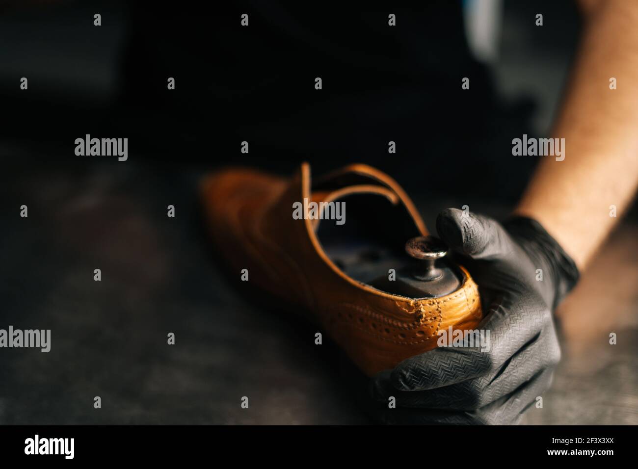 Close-up hands of shoemaker shoemaker wearing black gloves inserts ...