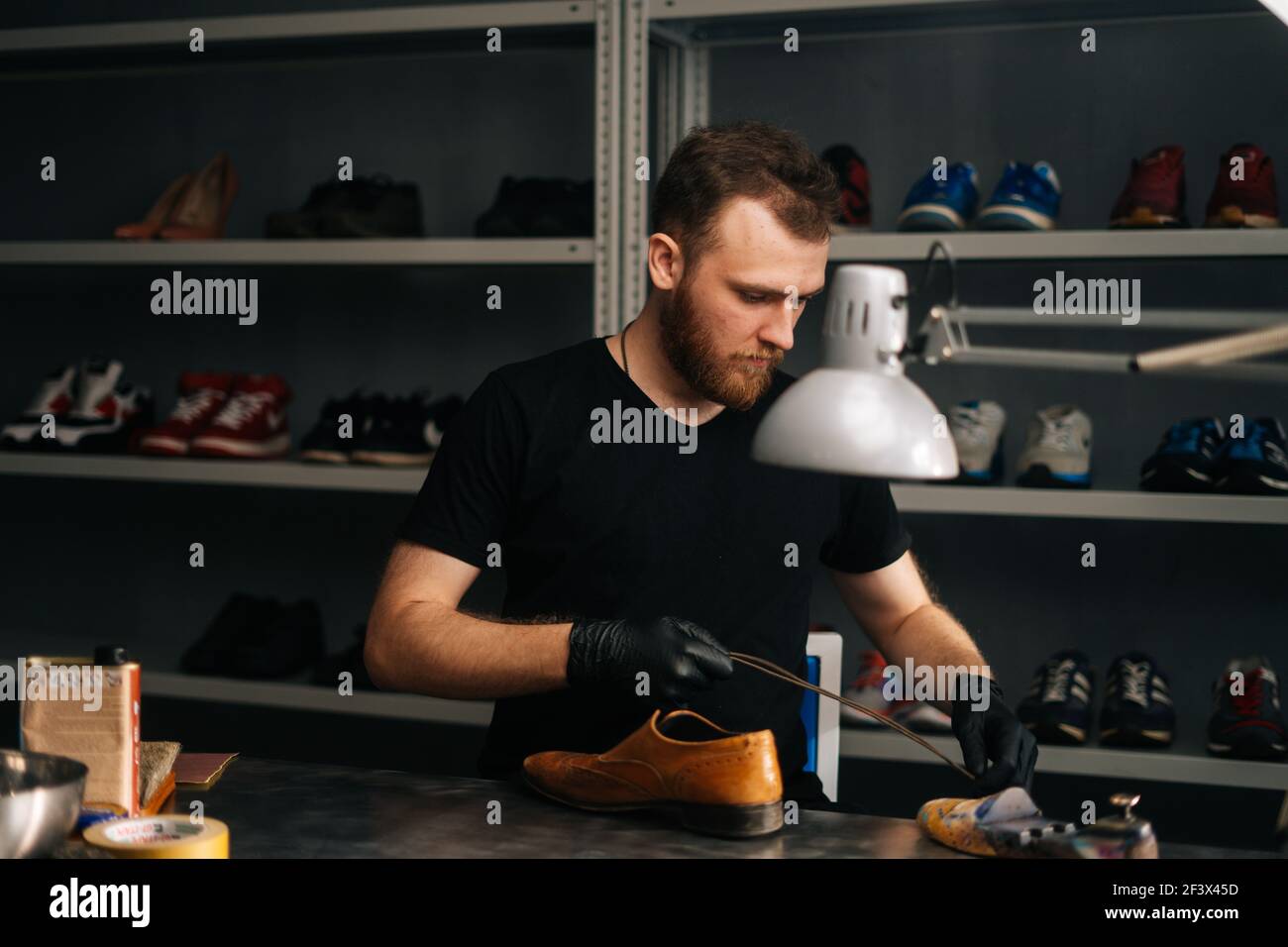 Portrait of shoemaker wearing black gloves inserts wooden shoe pad into ...