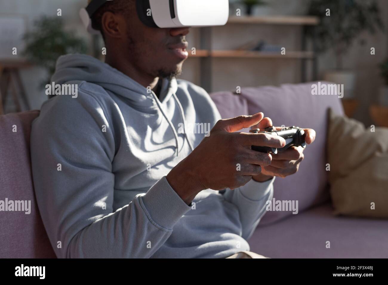 African American man in virtual reality headset playing interactive computer game indoors Stock Photo