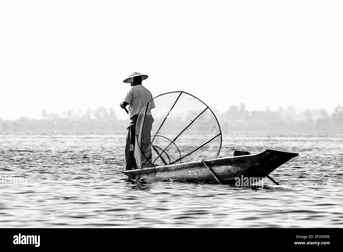 Traditional Burmese fisherman at Inle lake, one legged rowing style, the art of balance in perfection, Myanmar. Stock Photo