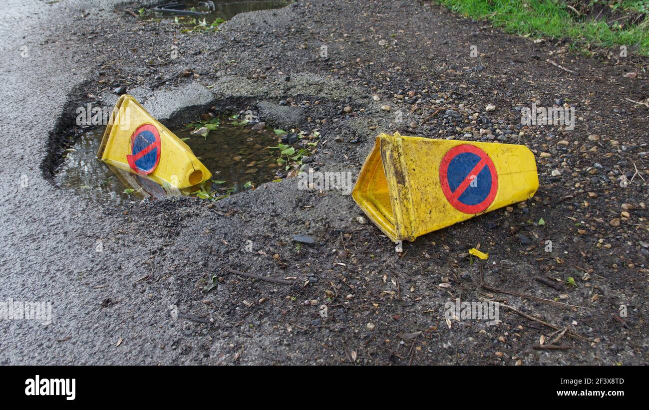 Two discarded yellow traffic warning cones discarded on rough ground Stock Photo