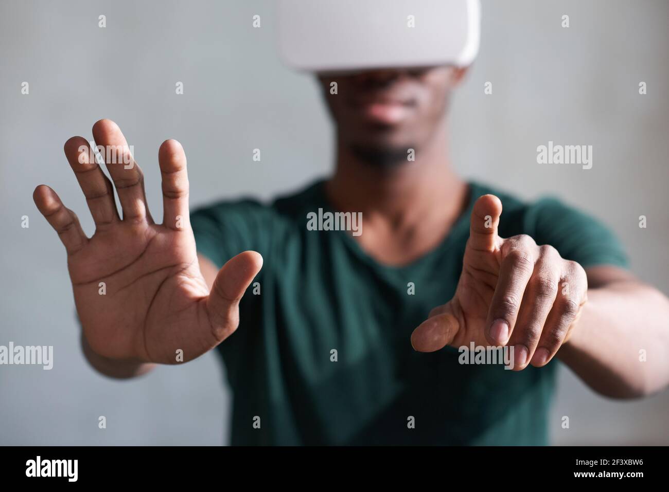 Black man in VR headset playing interactive video games, exploring augmented reality Stock Photo