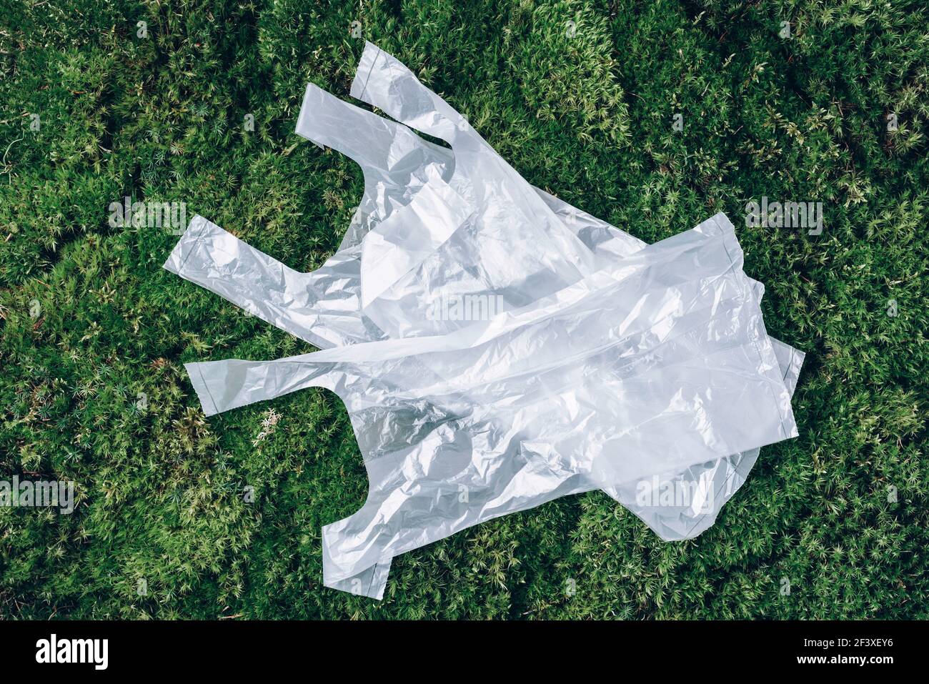 Disposable plastic bags on green moss, grass background. Pollution problem concept. Top view. Copy space. Environmental pollution problem. Garbage Stock Photo